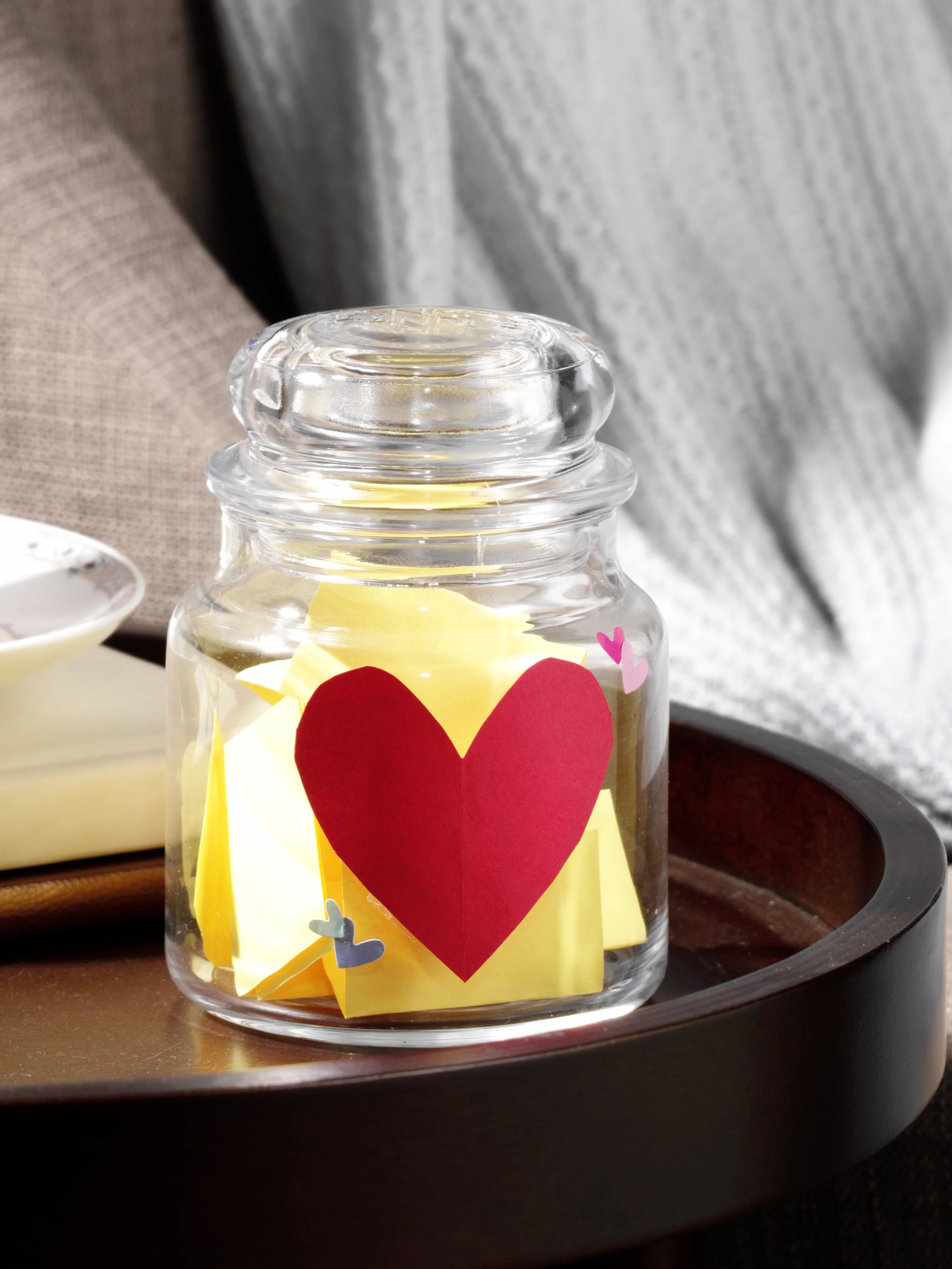 A jar of papers on wooden table inside a upcycled Yankee candle